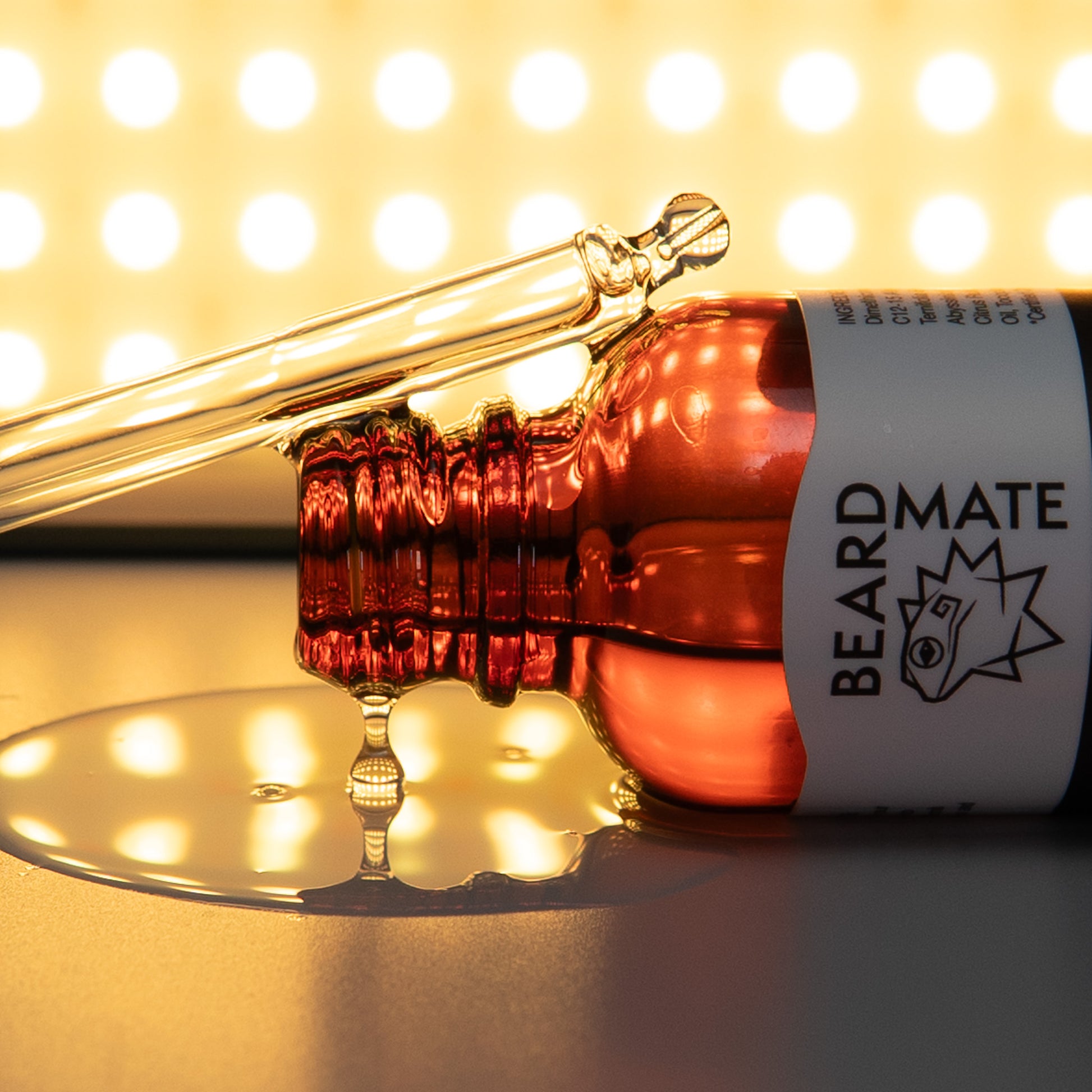 Beard oil dropper with 'BEARDMATE' label on a reflective surface with blurred lights in the background