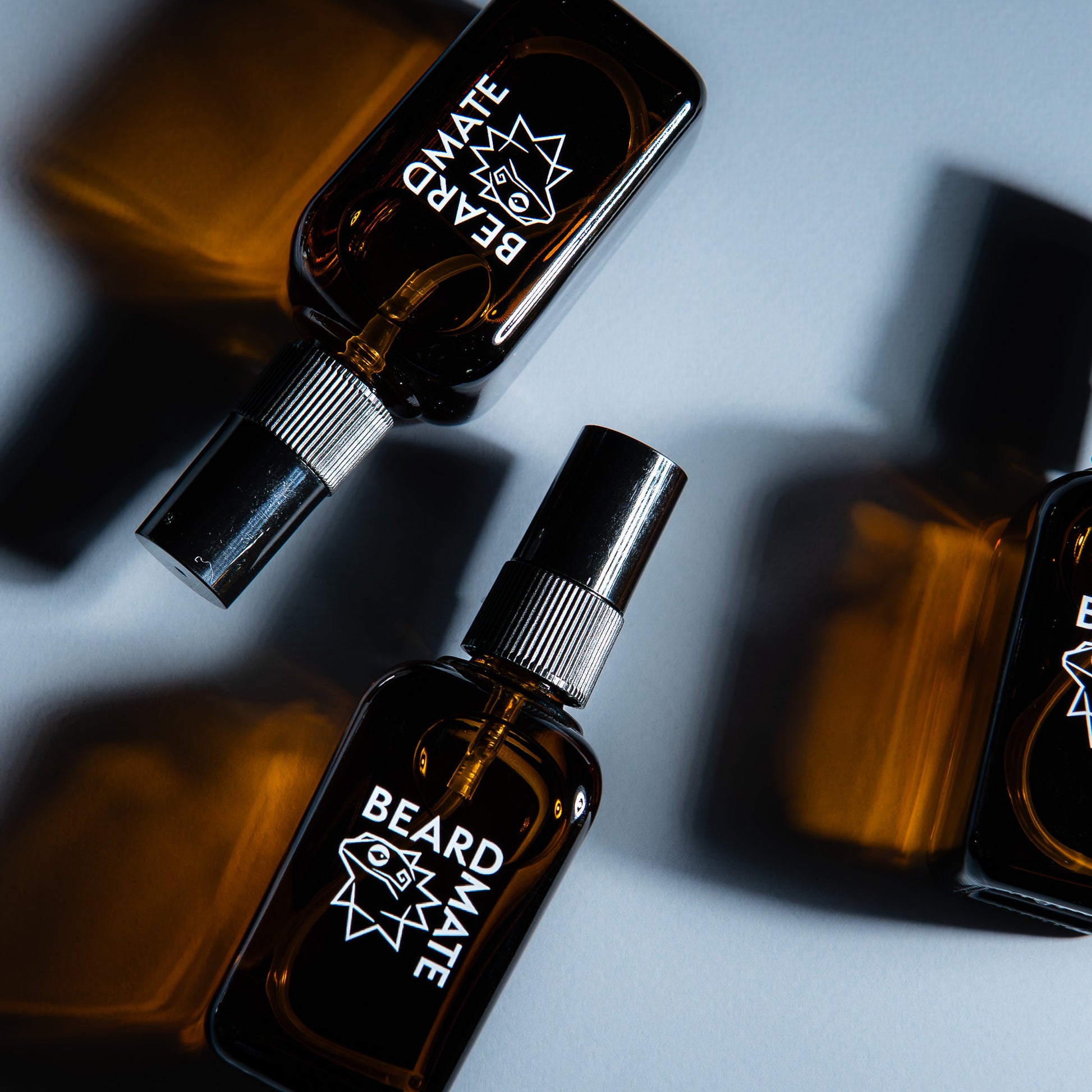 Three bottles of 'BEARDMATE' no-rinse spray on a gray background