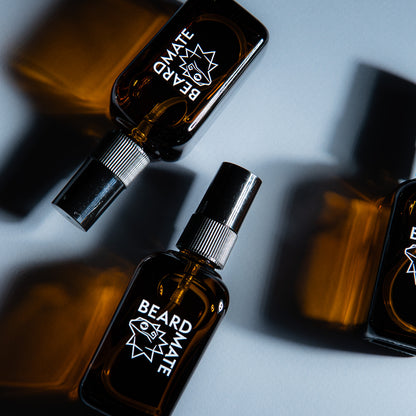 Three bottles of 'BEARDMATE' no-rinse spray on a gray background