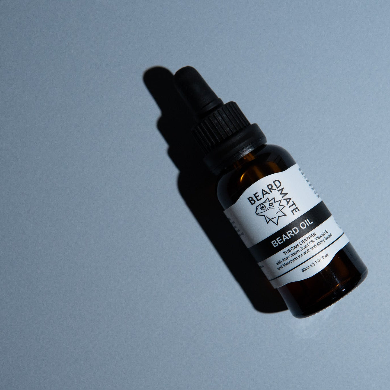 Bottle of beard oil with a label on a gray background